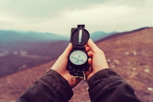 Hiker woman searching direction with a compass in the mountains. Point of view shot